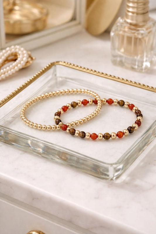 Two beaded bracelets on a glass tray with a marble surface